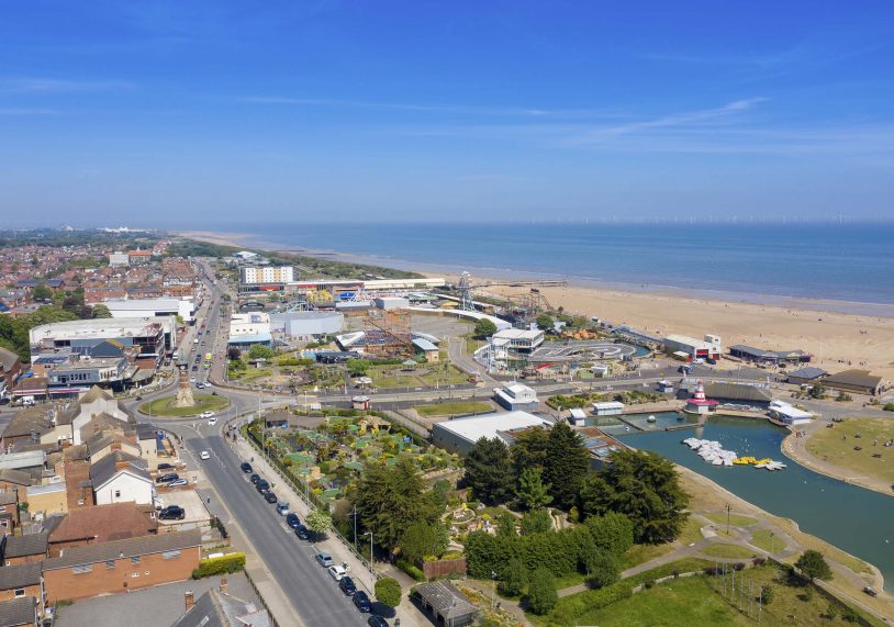 Aerial photo of the town centre of Skegness showing the pier on the sandy beach near fairground rides in the East Lindsey district of Lincolnshire, England on a beautiful sunny summers day.