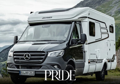 Modern silver motorhome travelling through an open countryside landscape