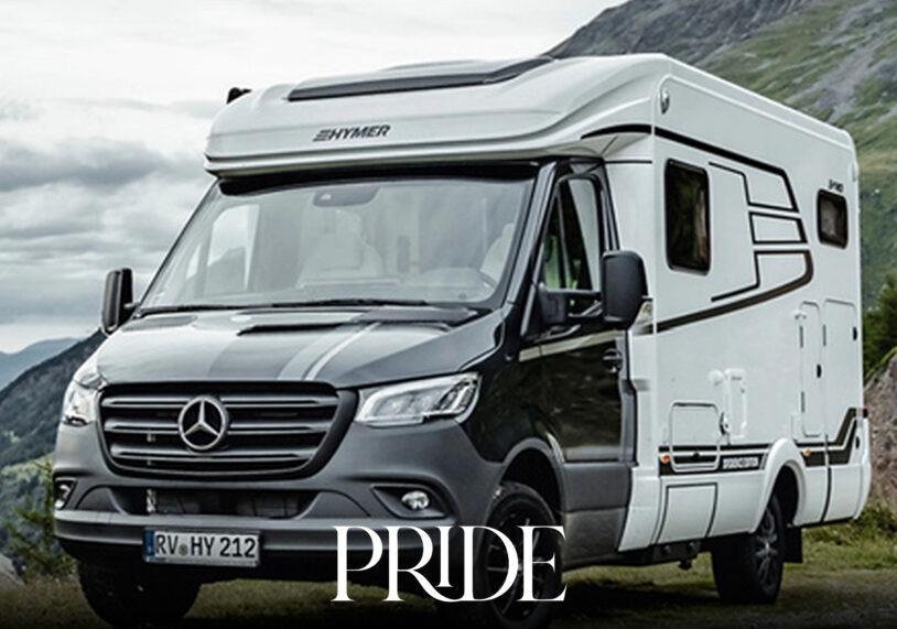 Modern silver motorhome travelling through an open countryside landscape