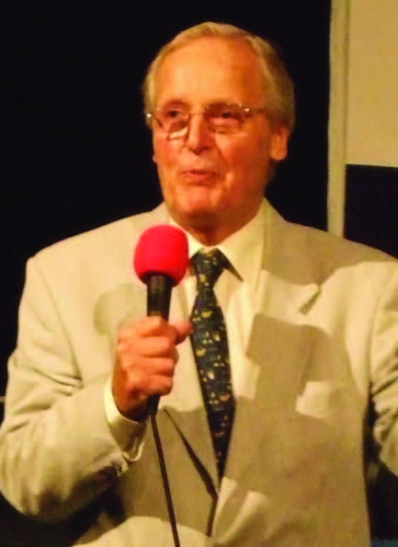 Colour photograph of Grantham-born broadcaster Nicholas Parsons speaking into a microphone.