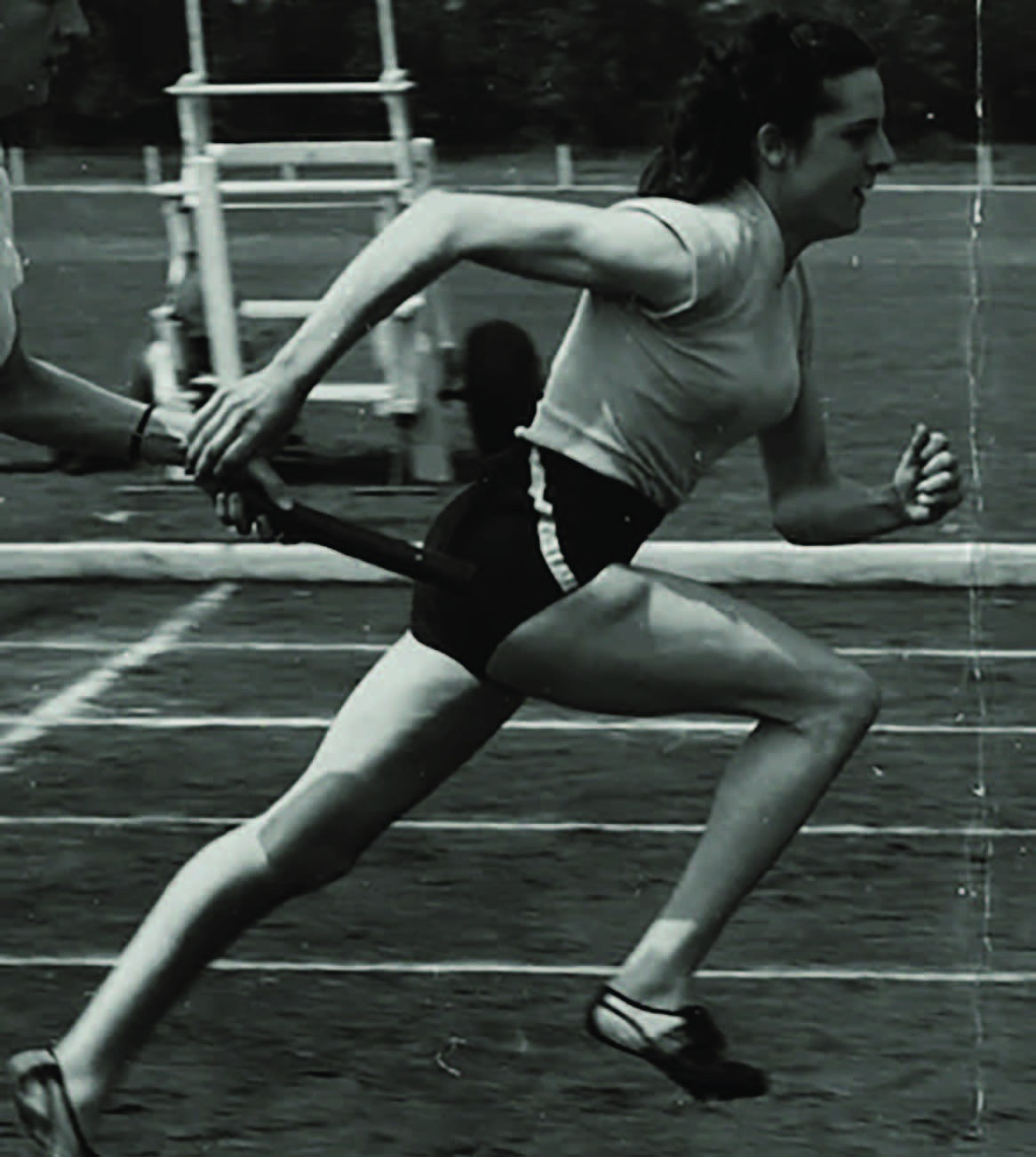Black-and-white action photograph of Lincolnshire sprinter and singer Anne Pashley running a relay.