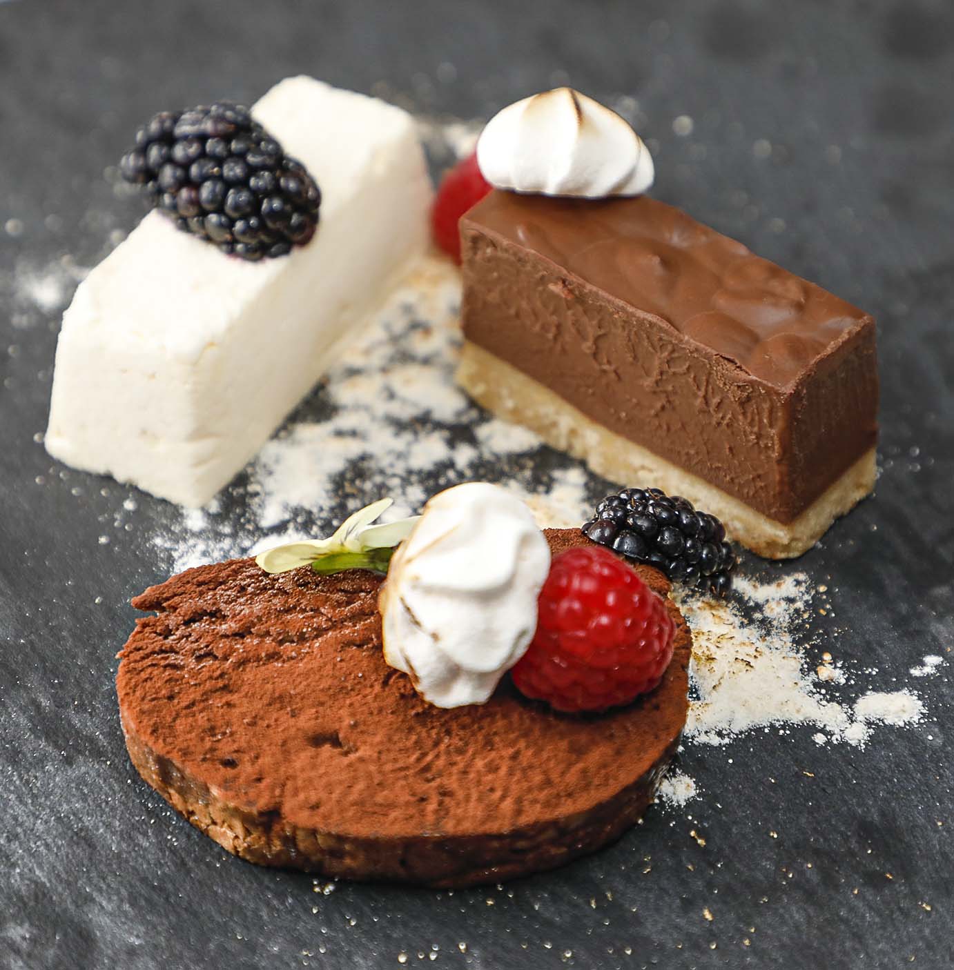 Trio of chocolate, comprising chocolate delice, white and vanilla chocolate parfait, chocolate roulade.