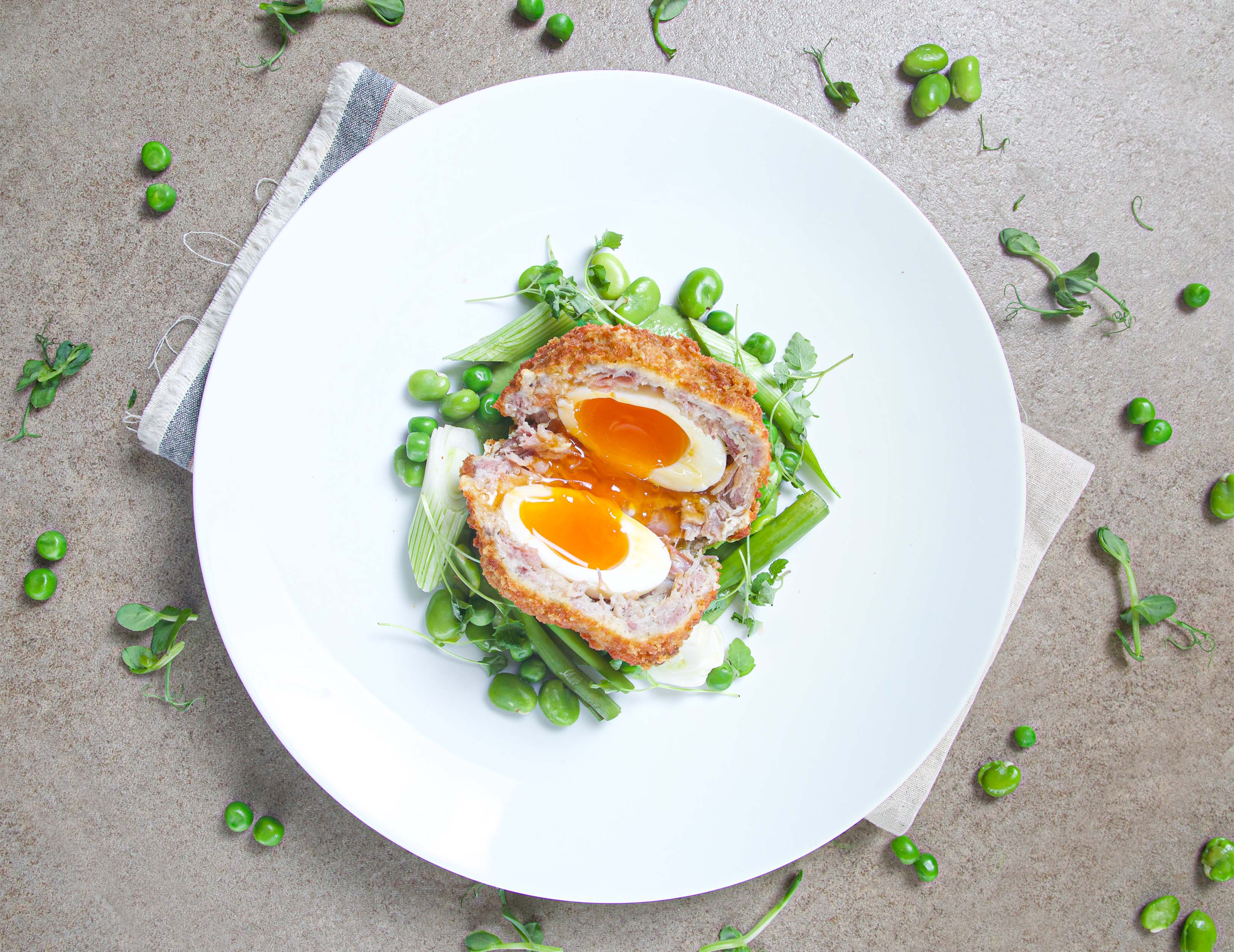 Ham hock Scotch egg with pea velouté, spring onion and broad bean.