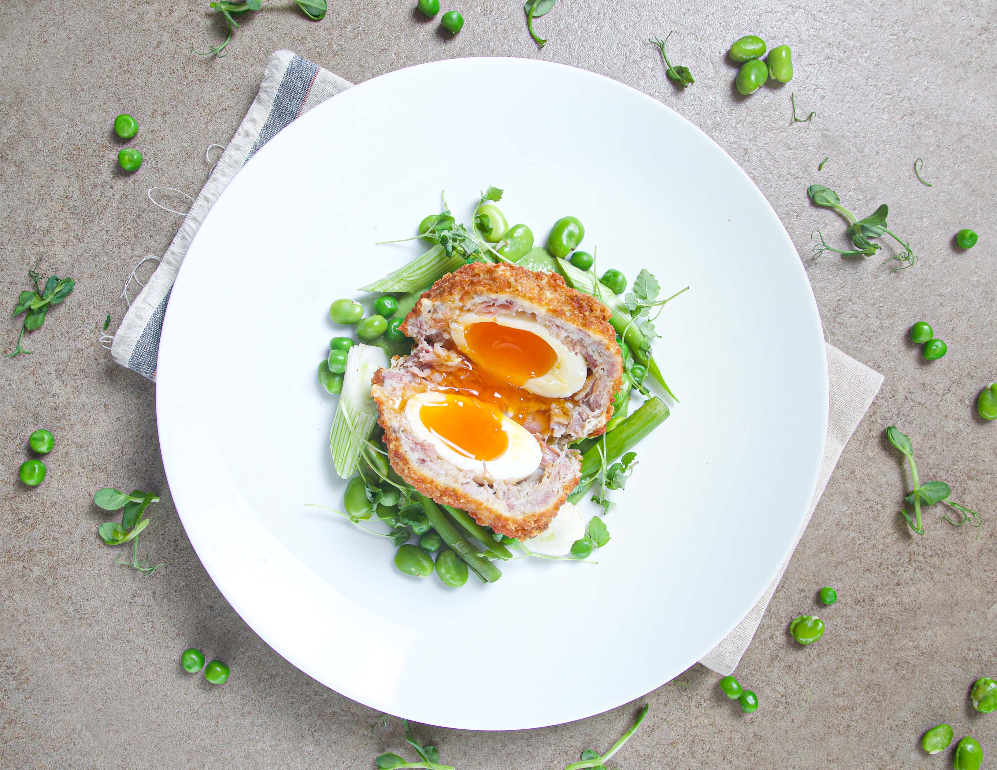 Ham hock Scotch egg with pea velouté, spring onion and broad bean.